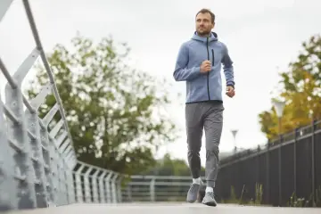 Mężczyzna w sportowym stroju biegnie po ścieżce. Idealny przykład, jak zacząć bieganie i cieszyć się ruchem na świeżym powietrzu.